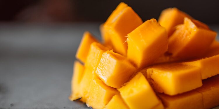 a sliced mango cubes on gray surface